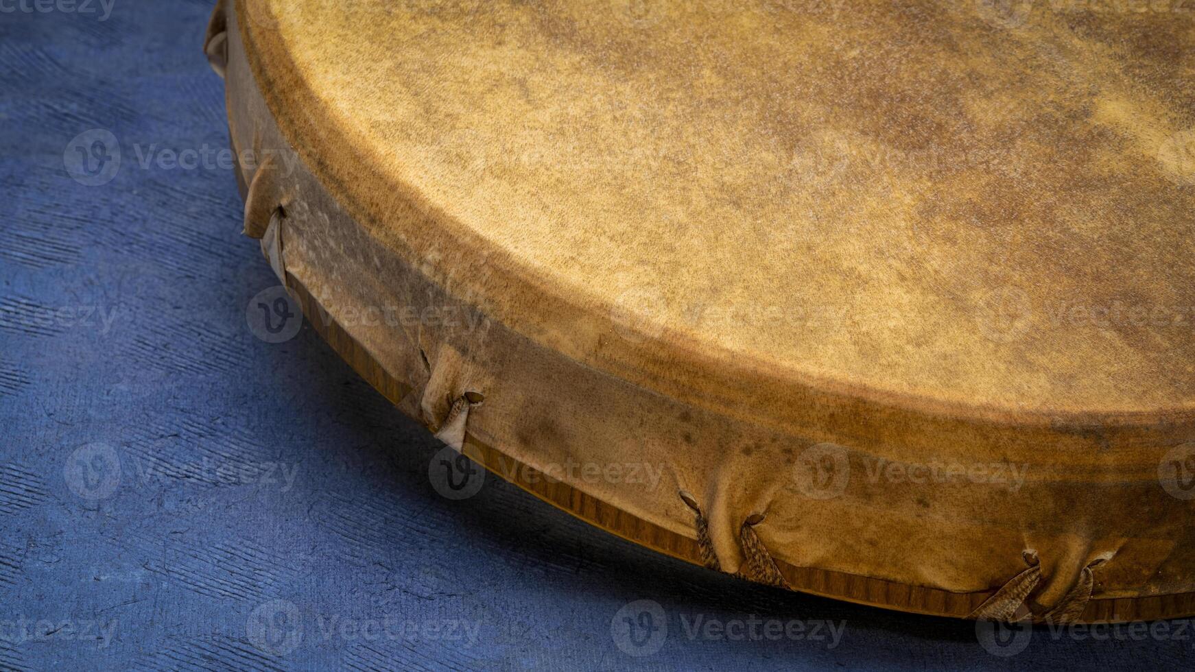 detail of handmade, native American style, shaman frame drum against textured blue paper photo