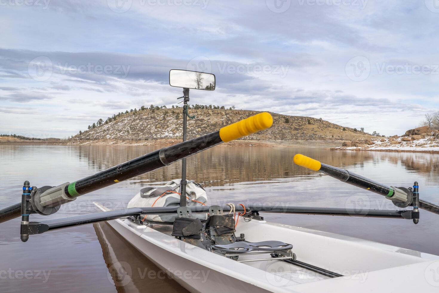 Coastal rowing shell with a mirror and dry bag on a shore of Carter Lake in northern Colorado in winter scenery. photo