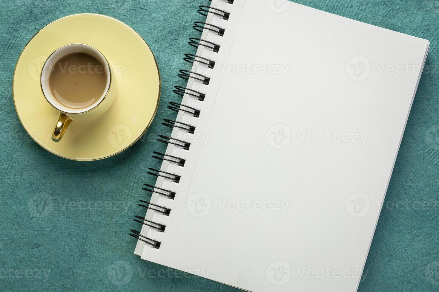 blank spiral sketchbook against textured paper with a cup of coffee, desktop flat lay photo