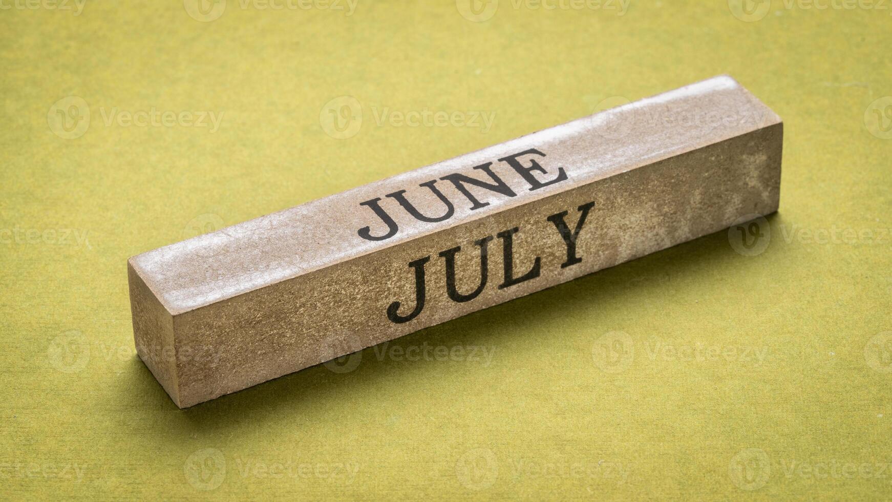 June and July text on grunge wooden block against handmade green rag paper, calendar concept photo