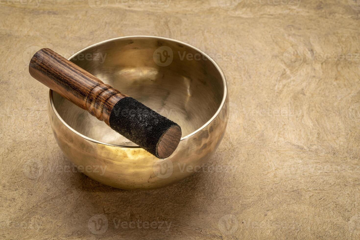 handmade tibetan singing bowl with a mallet on a textured bark paper, sound therapy for healing, relaxation and meditation photo