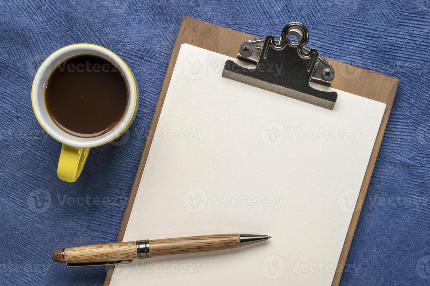 clipboard with a blank paper, desktop flat lay with a cup of coffee and a stylish pen photo