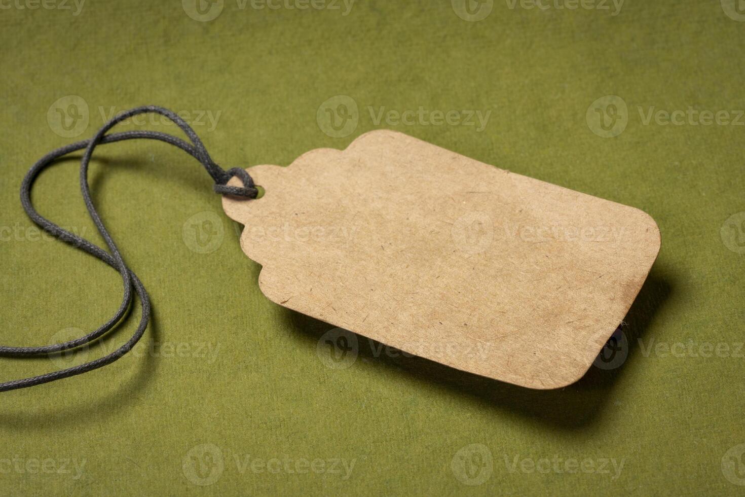 blank paper price tag with a twine against green, textured,  rag paper, shopping concept photo