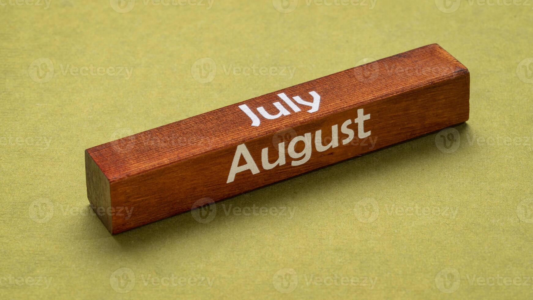 julio y agosto texto en de madera bloquear en contra hecho a mano verde papel, calendario concepto foto