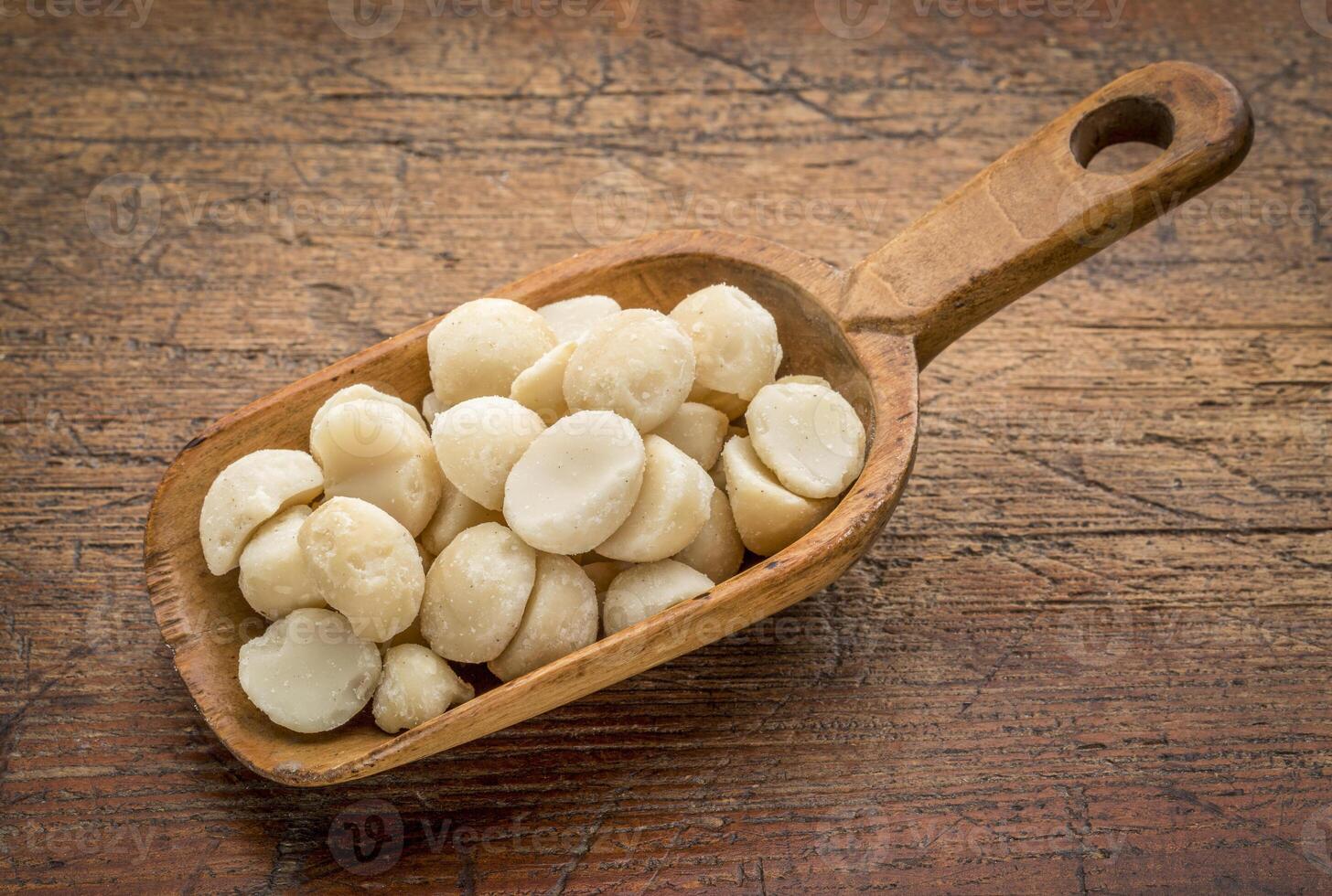 macadamia nuts on a rustic, wooden scoop against grunge wood photo