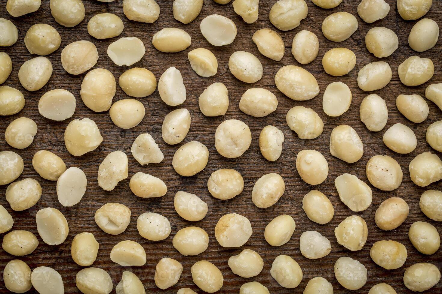 background texture of shelled macadamia nuts on rustic weathered wood - top view photo