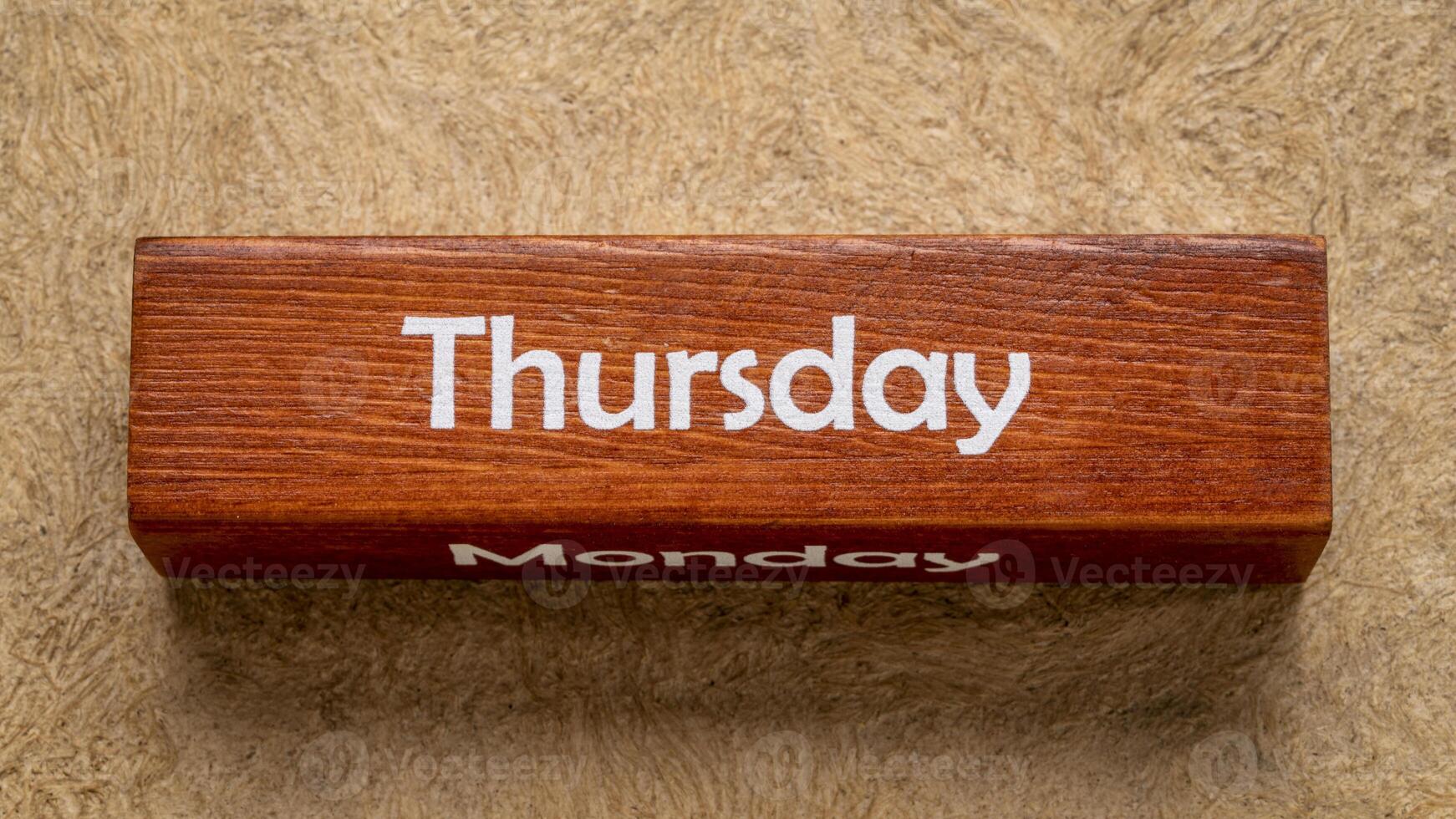 Thursday and Monday text on wooden block against handmade bark paper in earth tones, calendar concept photo