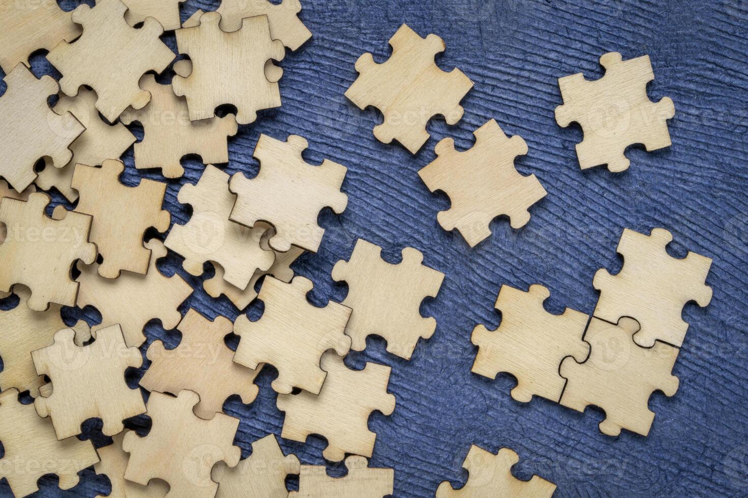 background of blank wooden jigsaw puzzle pieces on blue paper  background, completing a task or solving a problem concept photo