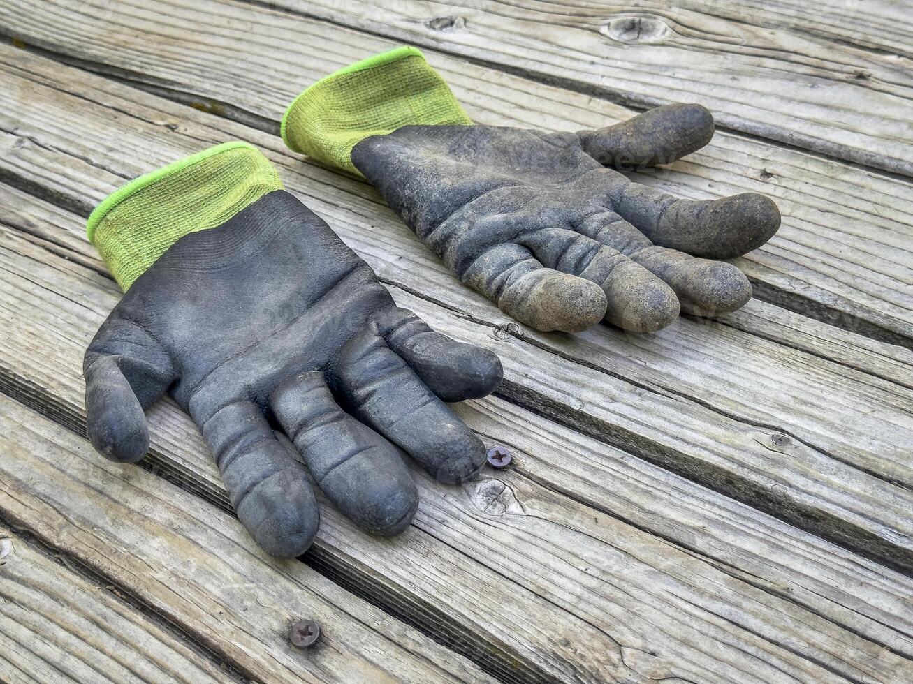 a pair of well used, dirty bamboo garden gloves on a wooden rustic deck photo