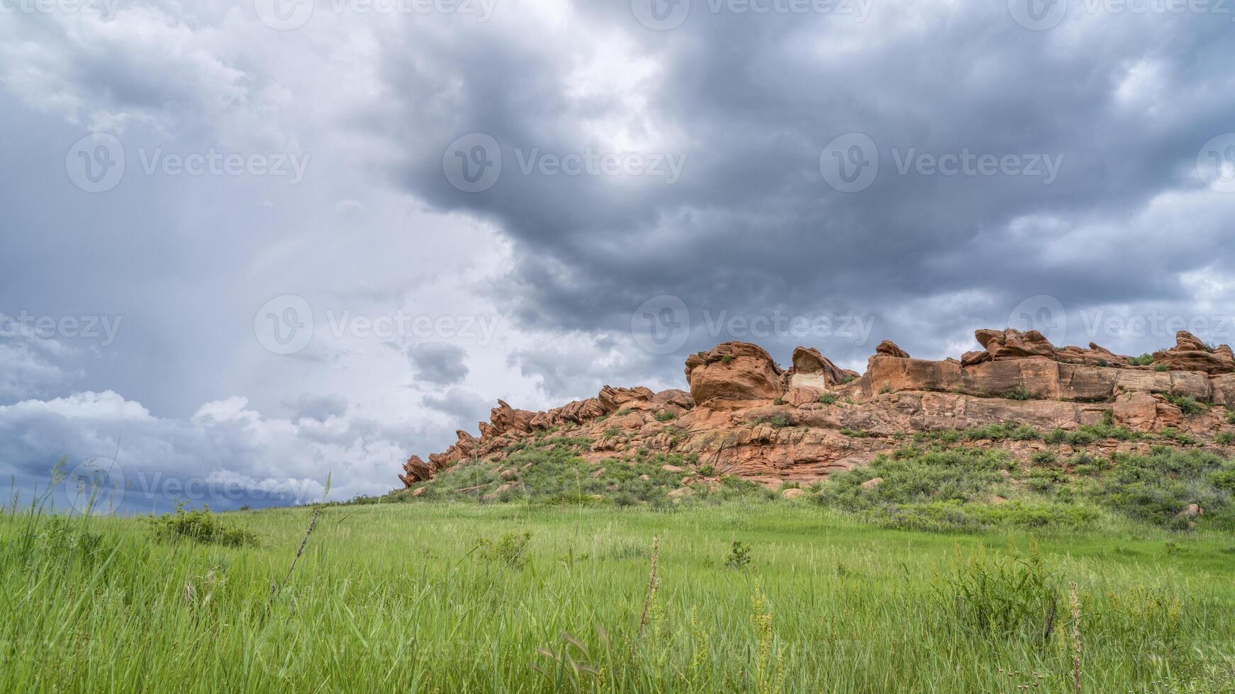 stormy clouds over sandstone cliff and green prairie in Colorado foothills - Lory State Park in late spring scenery photo