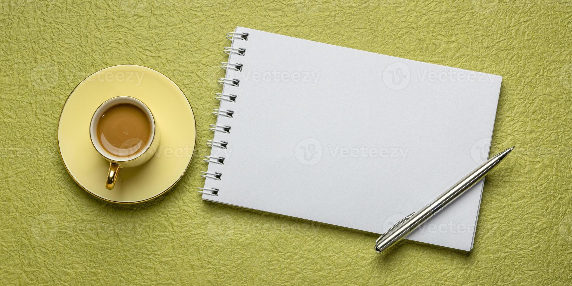 blank spiral sketchbook against textured paper with a cup of coffee, desktop flat lay photo