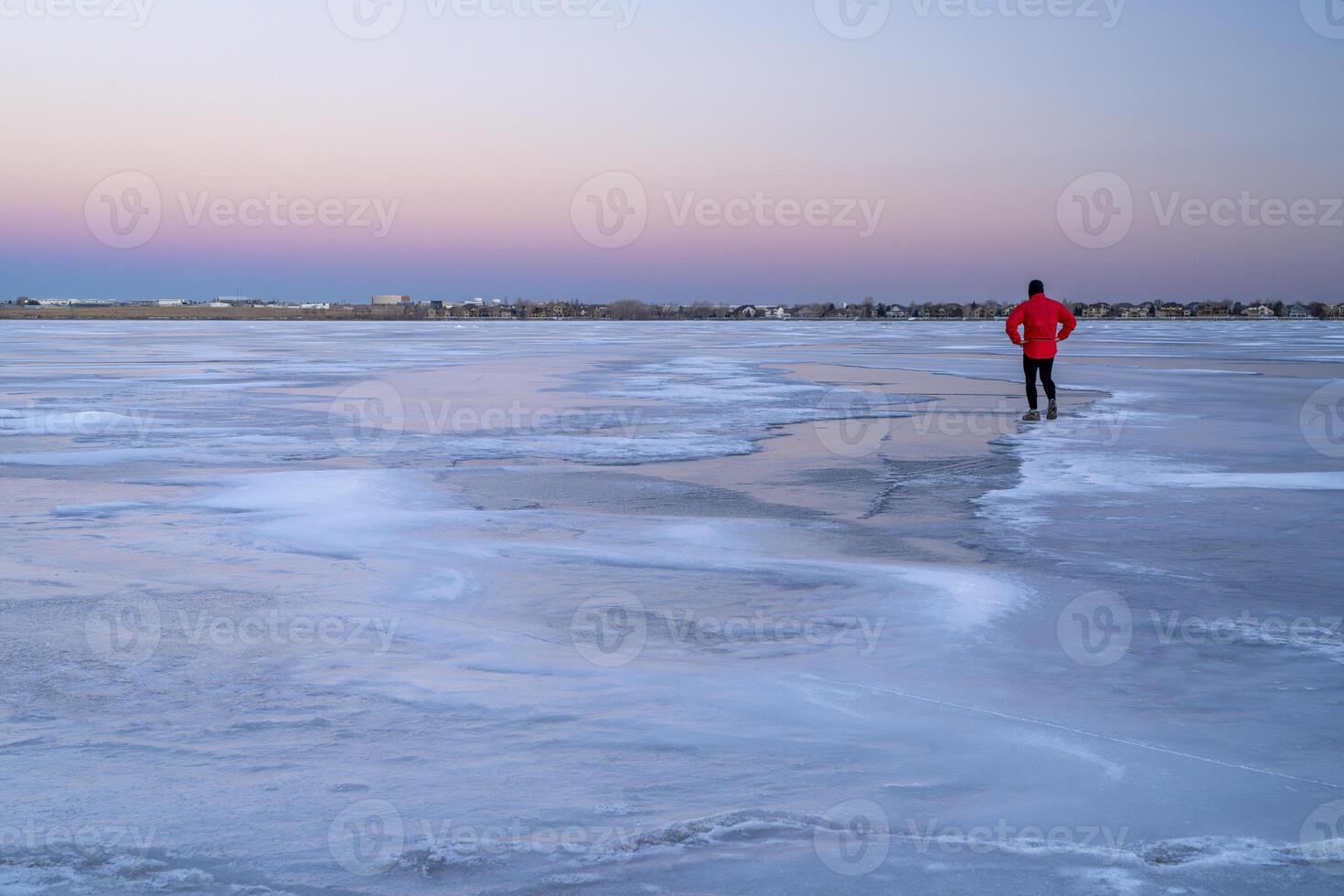 lonely male figure on a frozen lake at dusk in Colorado - Boyd Lake State Park photo