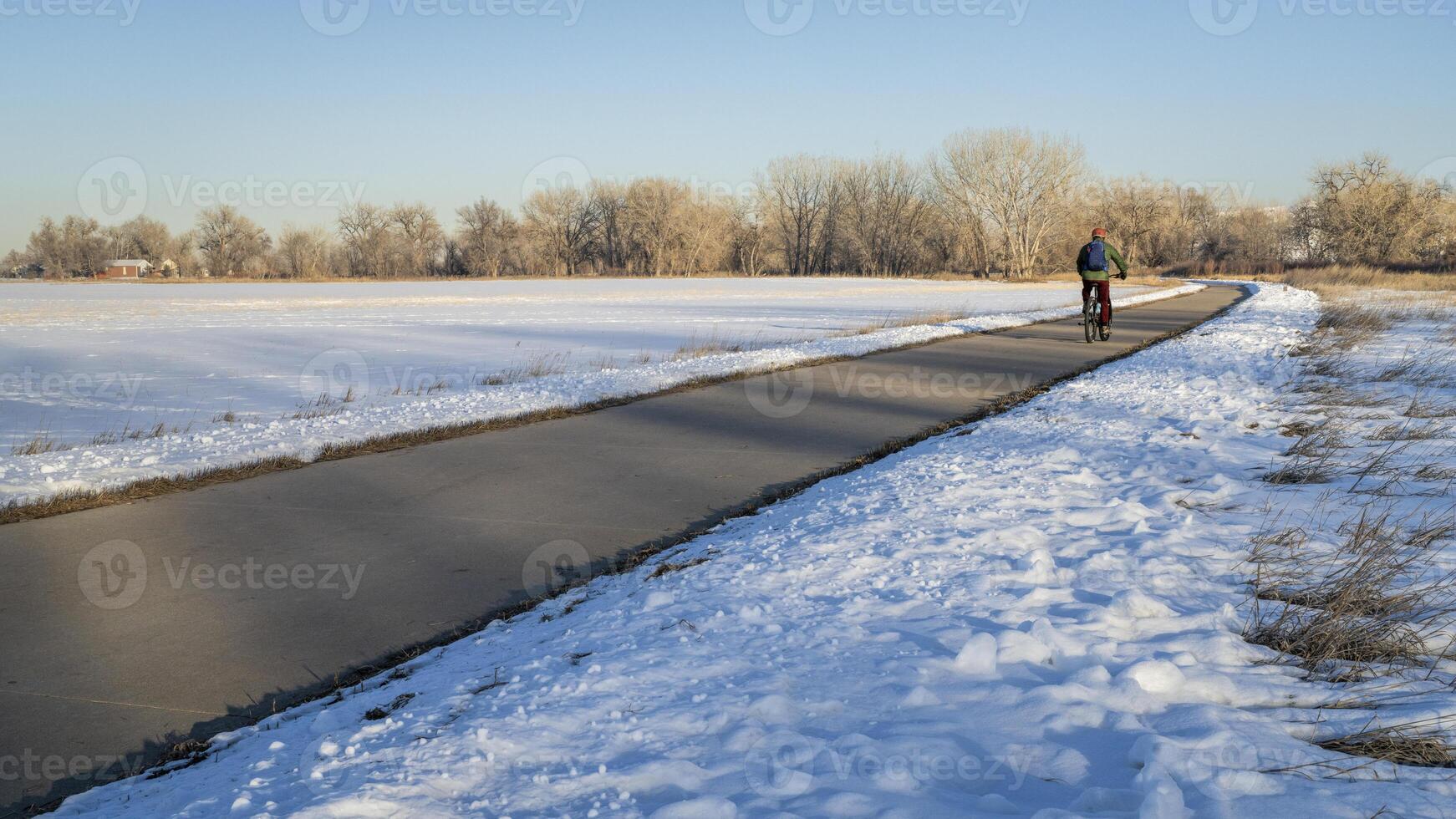 masculino ciclista desplazamientos en un bicicleta sendero en invierno paisaje - poudre río sendero en del Norte Colorado Entre Windsor y Greeley foto