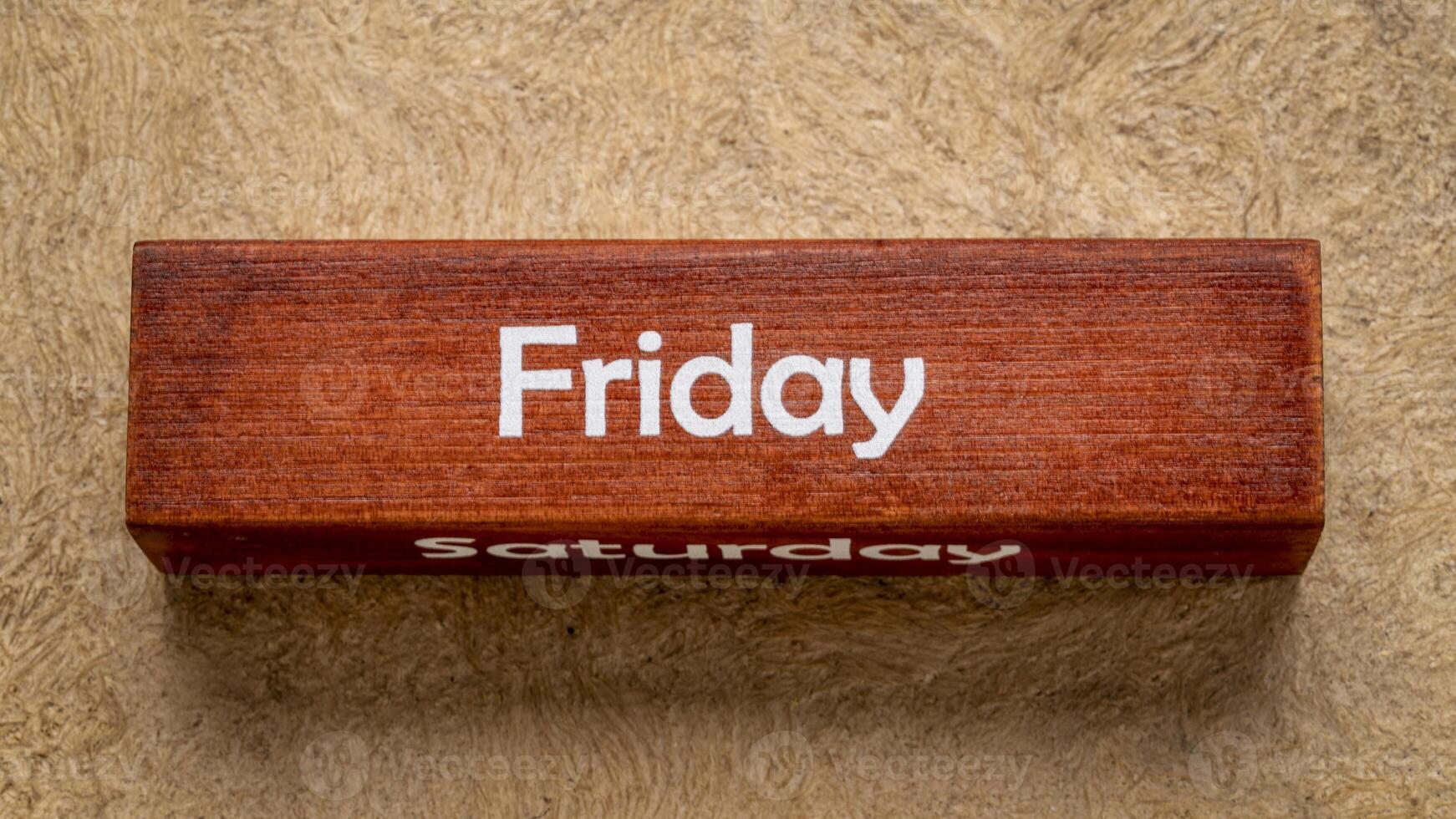 Friday and Saturday text on wooden block against handmade bark paper in earth tones, calendar concept photo