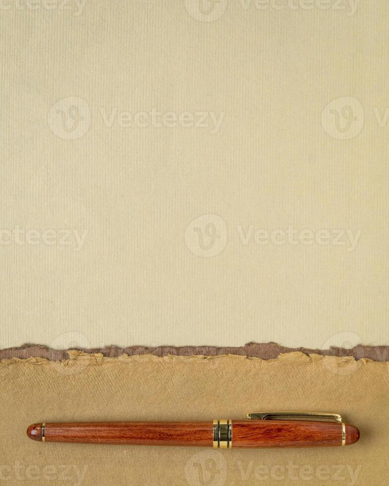 abstract paper landscape in pastel earth tones tones - collection of handmade rag papers with a wooden luxury pen photo