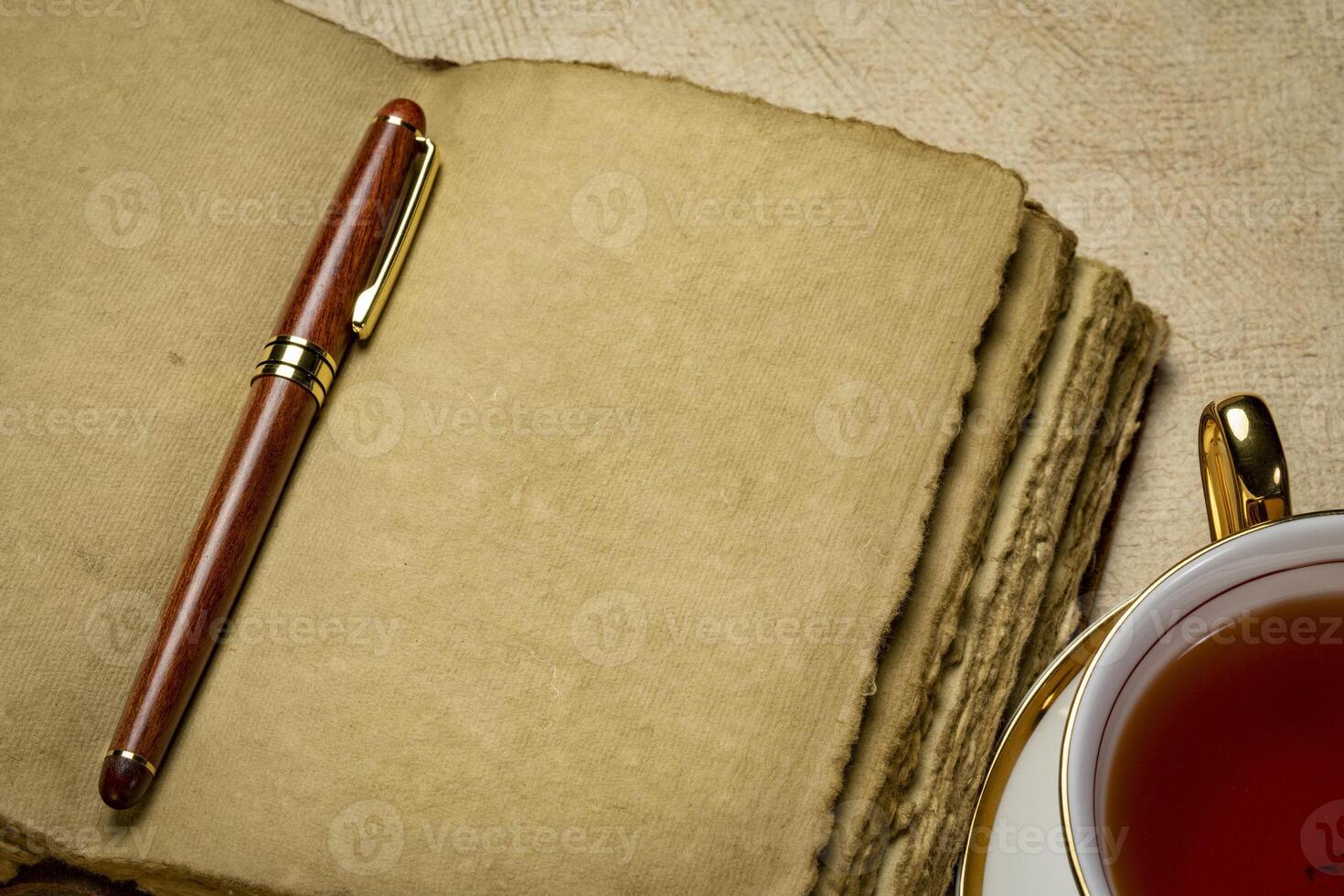 blank retro leather-bound journal with decked edge handmade paper pages with a stylish pen and a cup of tea, journaling concept photo