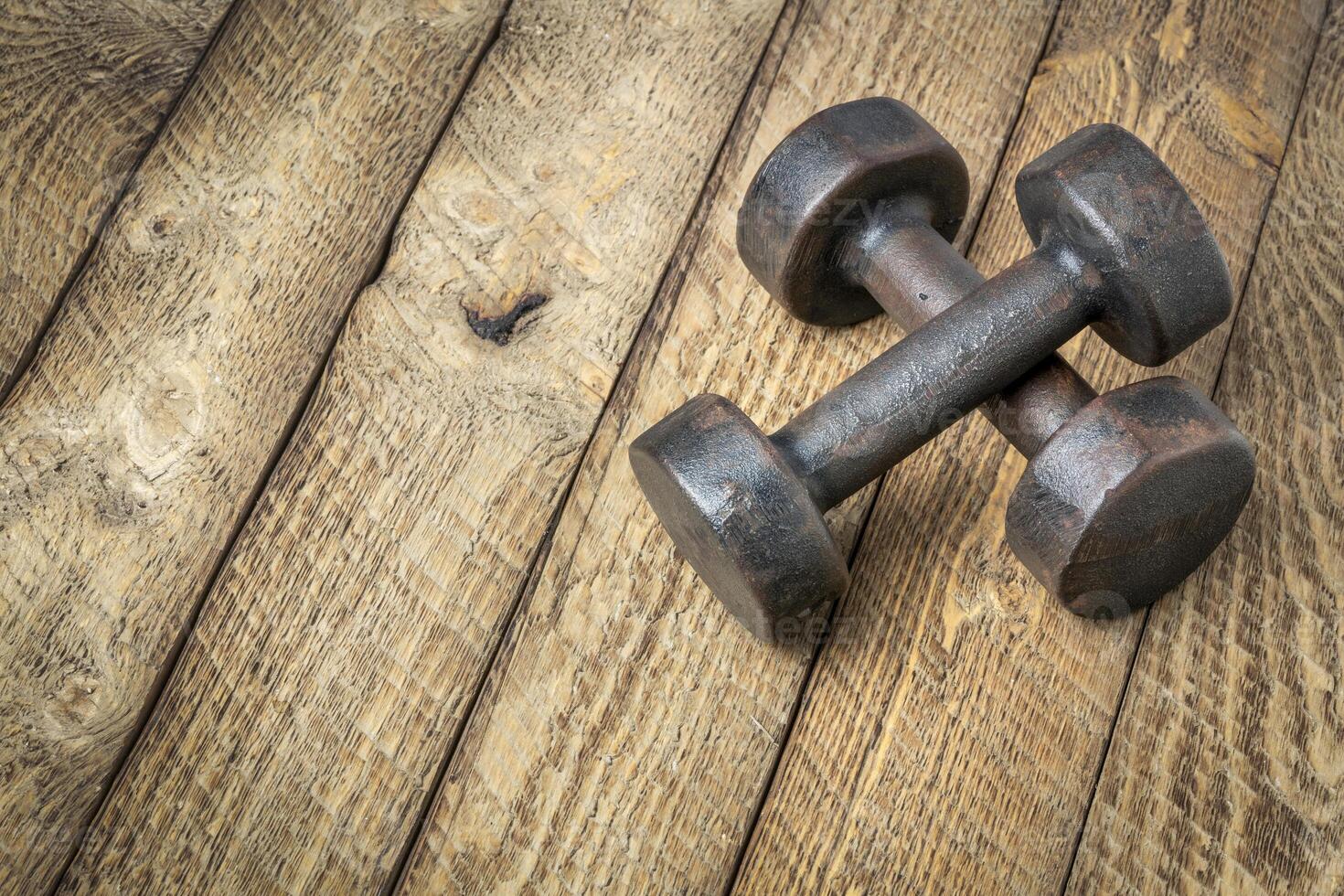 a pair of vintage iron rusty dumbbells on a grained barn wood background, fitness concept photo