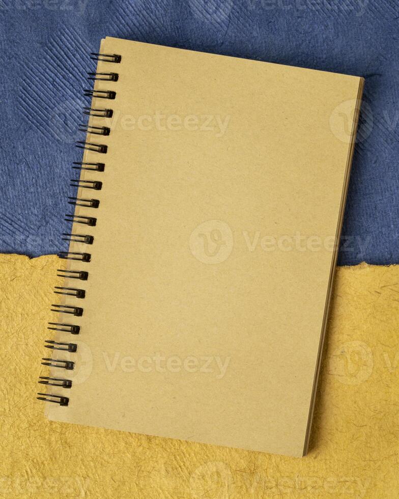 blank notebook against paper abstract in colors of Ukrainian national flag - blue and yellow photo