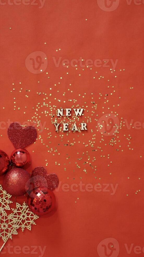 Christmas flatley with New Year lettering on red gold background baubles decoration. Close-up, shiny composition. Postcard . Vertical photo