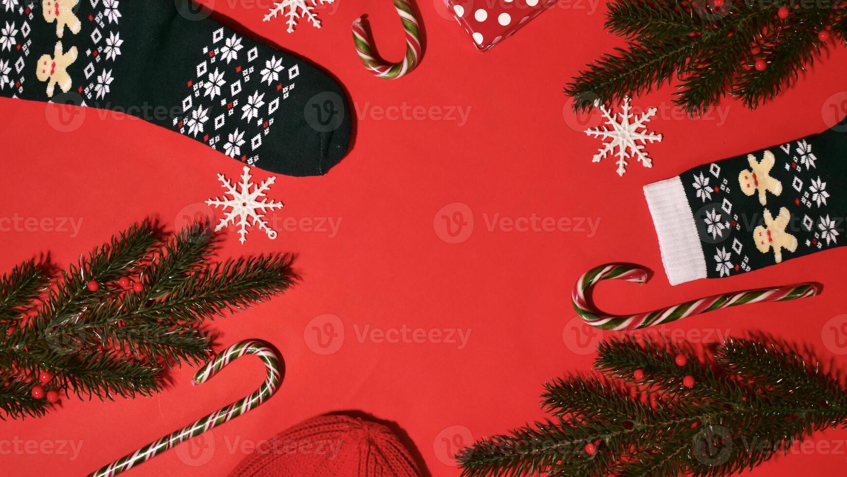 Festive Christmas Frame on Red Background on New Year 2024 with Branch, Gift, Hat, Candy Caramel, Snowflakes, Socks. Top view, close-up, flatlay, copy space, composition photo