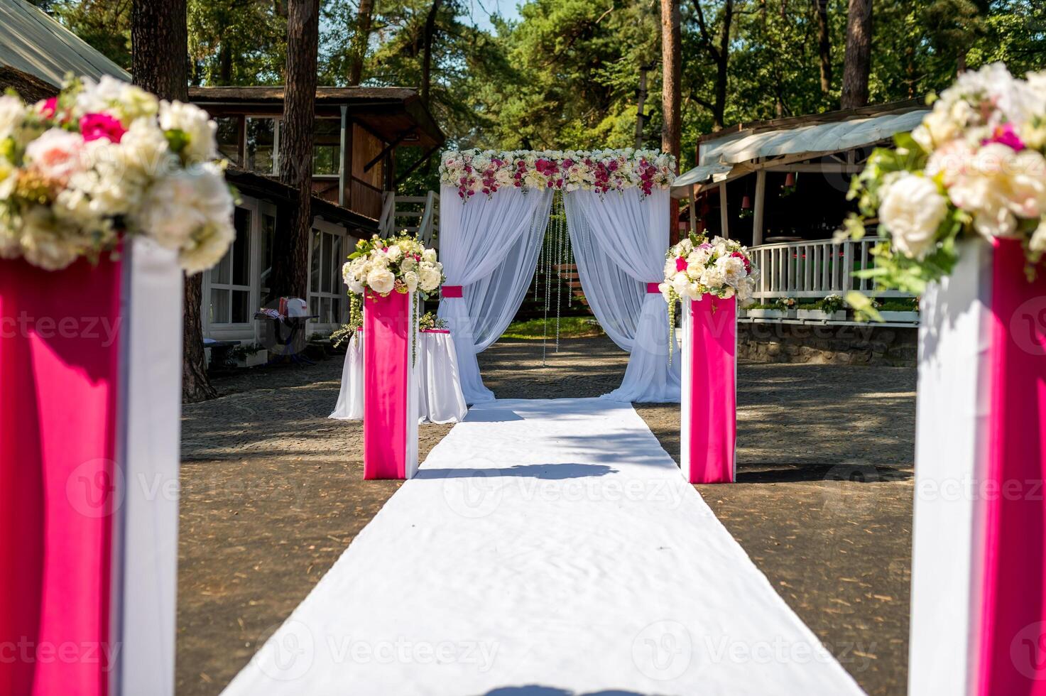 Beautiful wedding ceremony outdoors. Wedding arch made of cloth and white and pink flowers on a restaurant background. photo