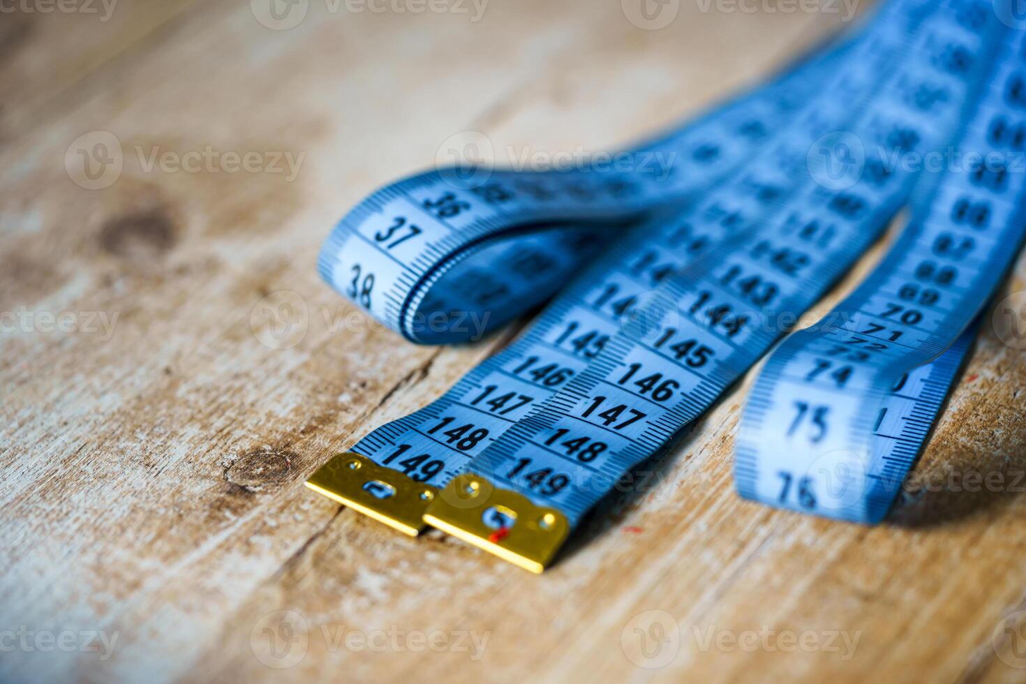 Blue measuring tape on wooden table. Tailor concept. Close-up. photo