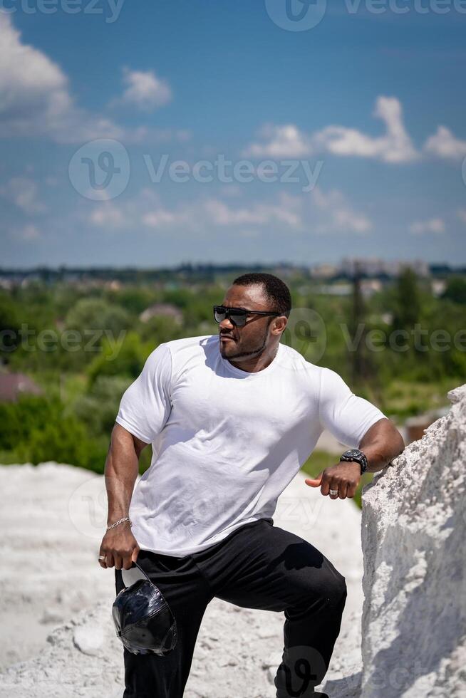 Handsome athletic man in white shirt standing outdoor. Strong big man in sunglasses outdoor. photo