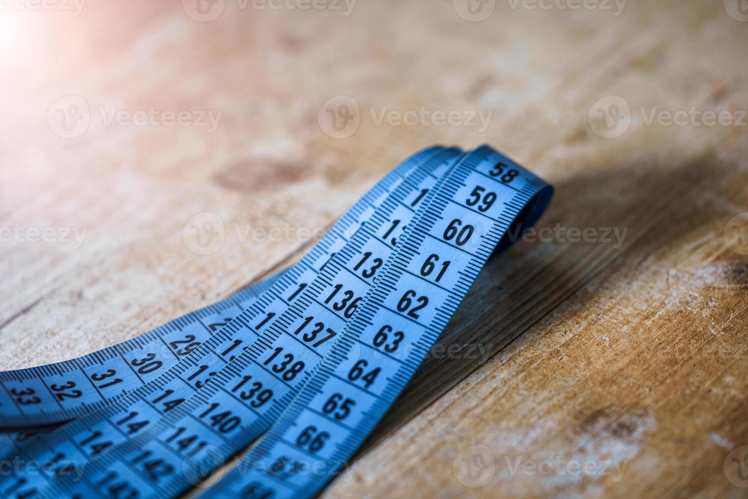 Curved measuring blue tape on wooden table. Tailor s concept. Diet and dieting concept. photo