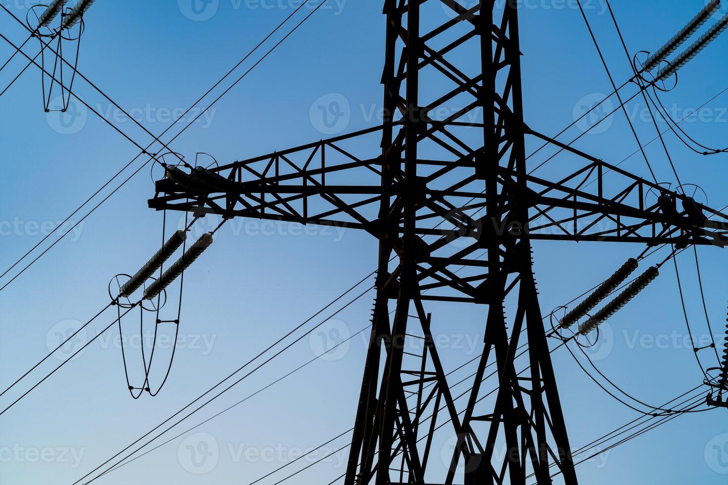 Pylons or transmission towers in countryside on beautiful blue sky background. Landscape with high-voltage transmission towers. photo