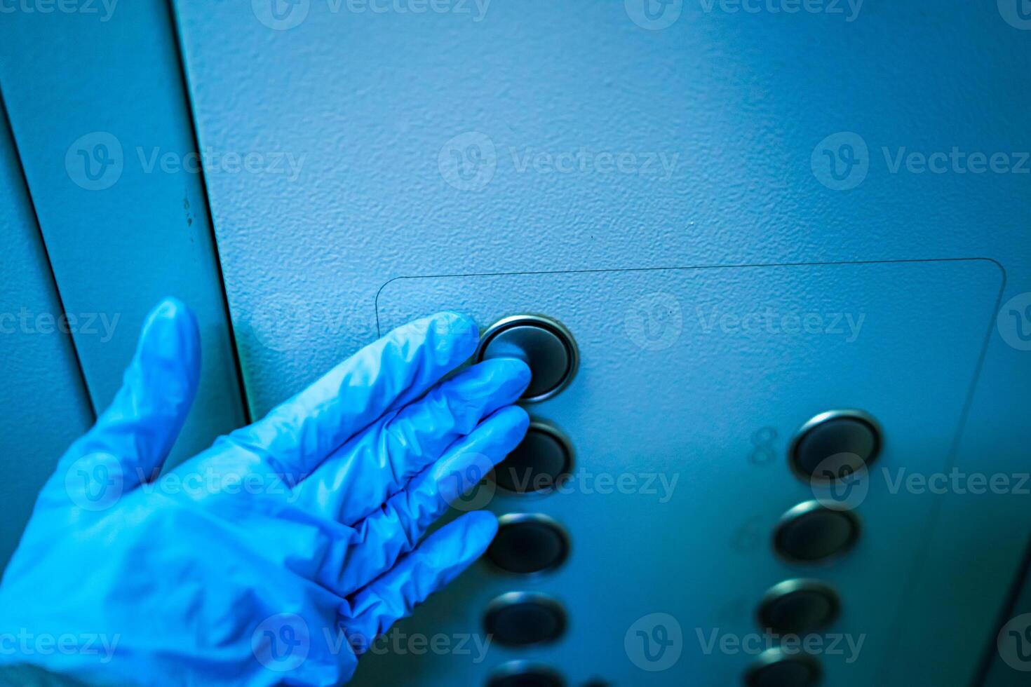 Man presses elevator button during flu covid virus outbreak. Blue gloves in hands. Coronovirus epidemic. Pneumonia. COVID-19 and coronavirus. Pandemic. photo