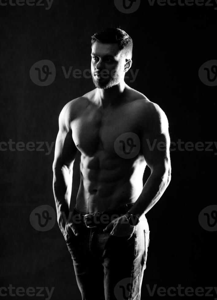 Muscular and sexy man. Naked torso of young man with perfect abs. Black and white. Half turned to the camera. Closeup. photo