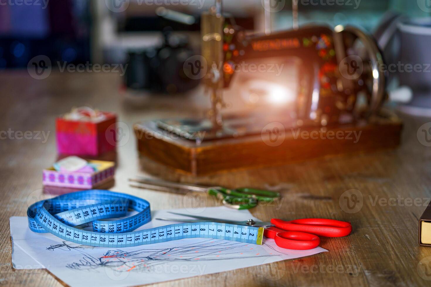 Blue measuring tape and scissors with red handle on sketches with dresses. Tailor s sketches, design work. Draft with beautiful dresses on table. Tailor concept. Close-up. photo