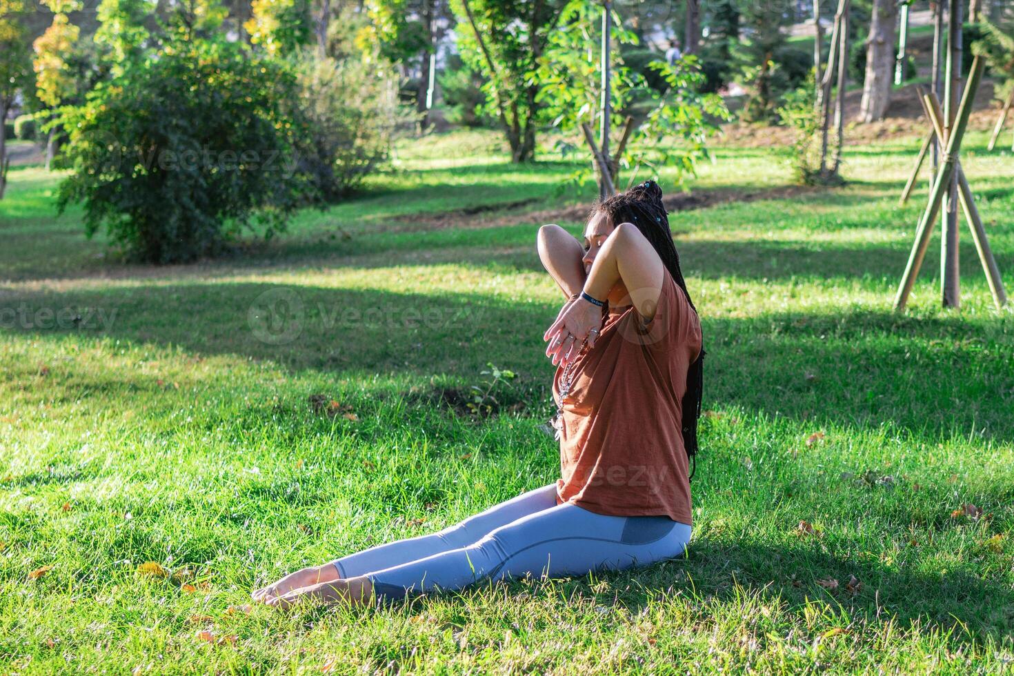 Woman is doing yoga asana outside in a park. Concept of balancing and healthy lifestyle. photo