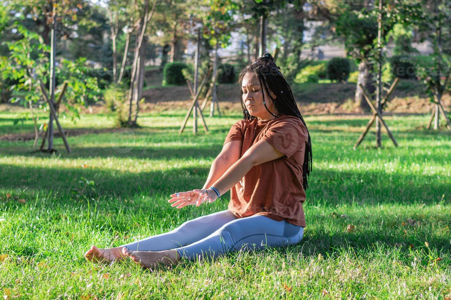 Woman is doing yoga asana outside in a park. Concept of balancing and healthy lifestyle. photo