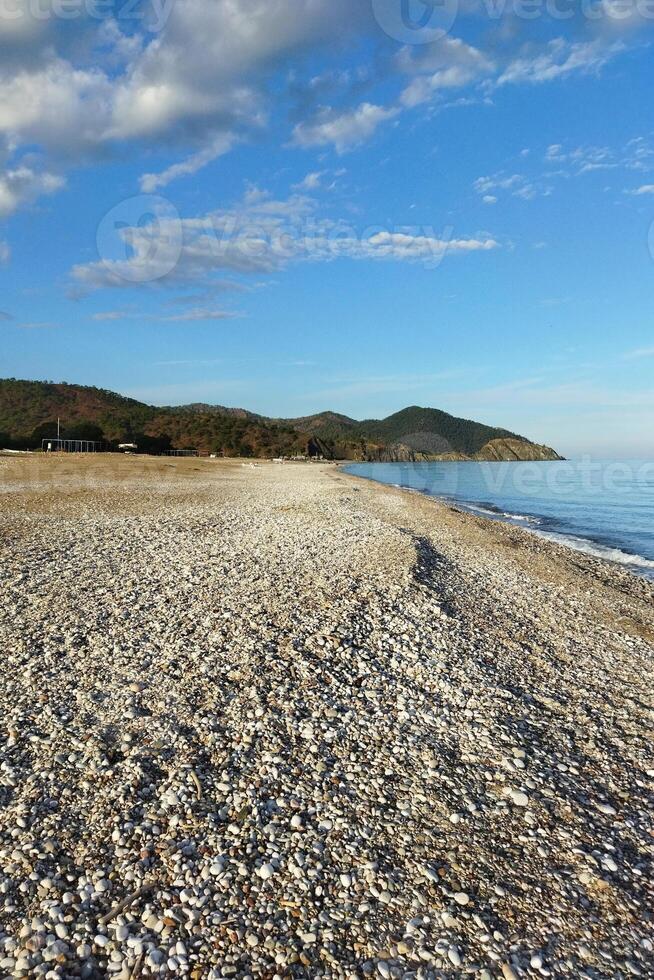 Tranquil Sunset View Pebble Beach Stretching to Distant Mountains under Blue Sky photo