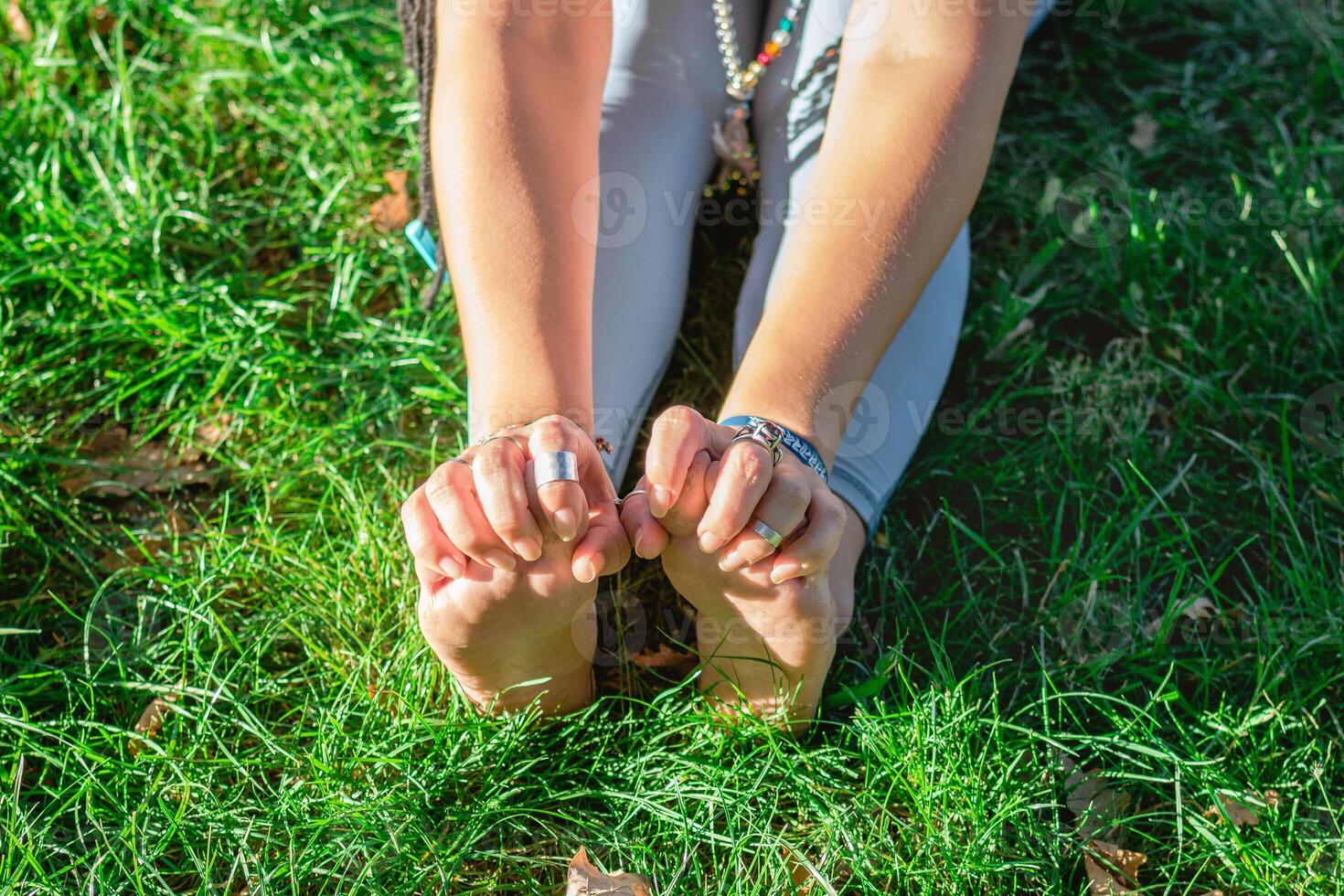 cerca arriba manos y piernas de mujer haciendo yoga ejercicio en un césped en un parque. concepto de sano estilo de vida. foto