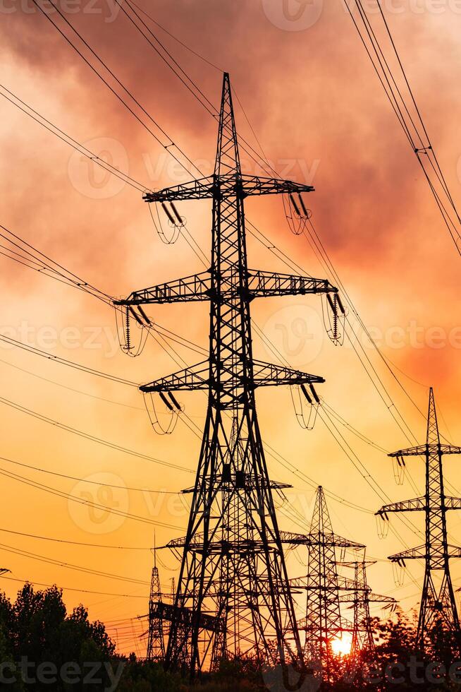 Metal construction silhouette. Electrical supply tower shadows on orange sunset. photo