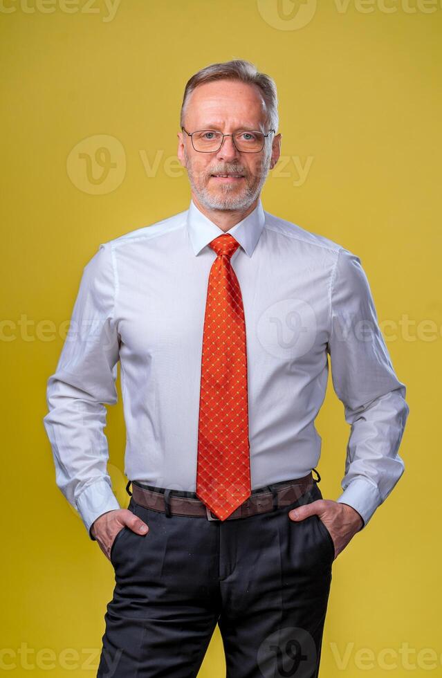 retrato de un mayor hombre sonriente. hombre mirando a cámara. negocio hombre en estudio, amarillo fondo hombre en lentes retrato foto