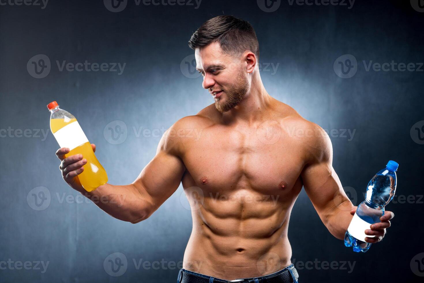 Sportsman holding a bottle of water and soda. Choosing between healthy and harmful drink. Portrait. Looking at camera. Closeup photo