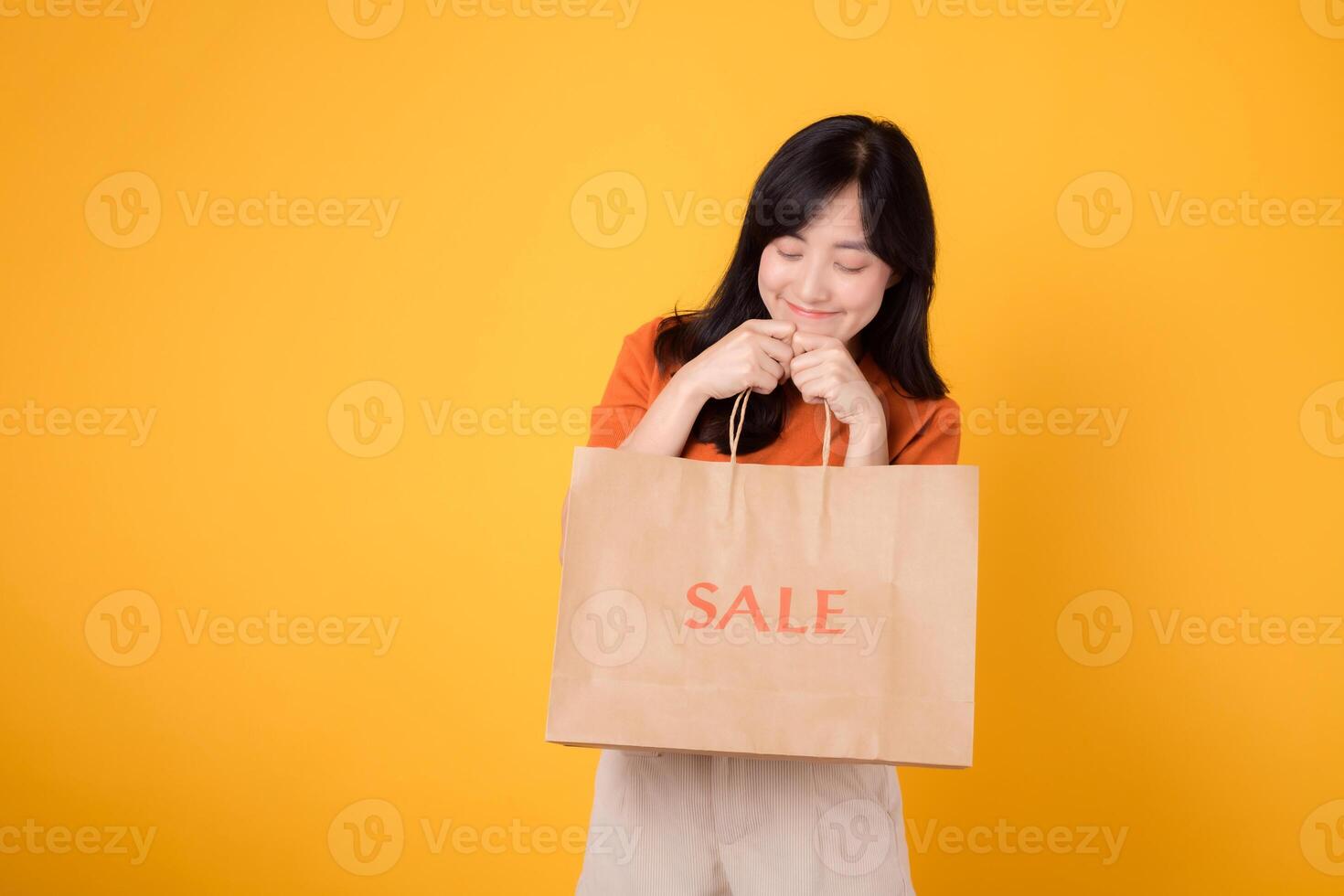 Uncover the thrill of surprising deals and joyful shopping. Young woman in her 30s presents her purchases, capturing the excitement of the best bargains. photo