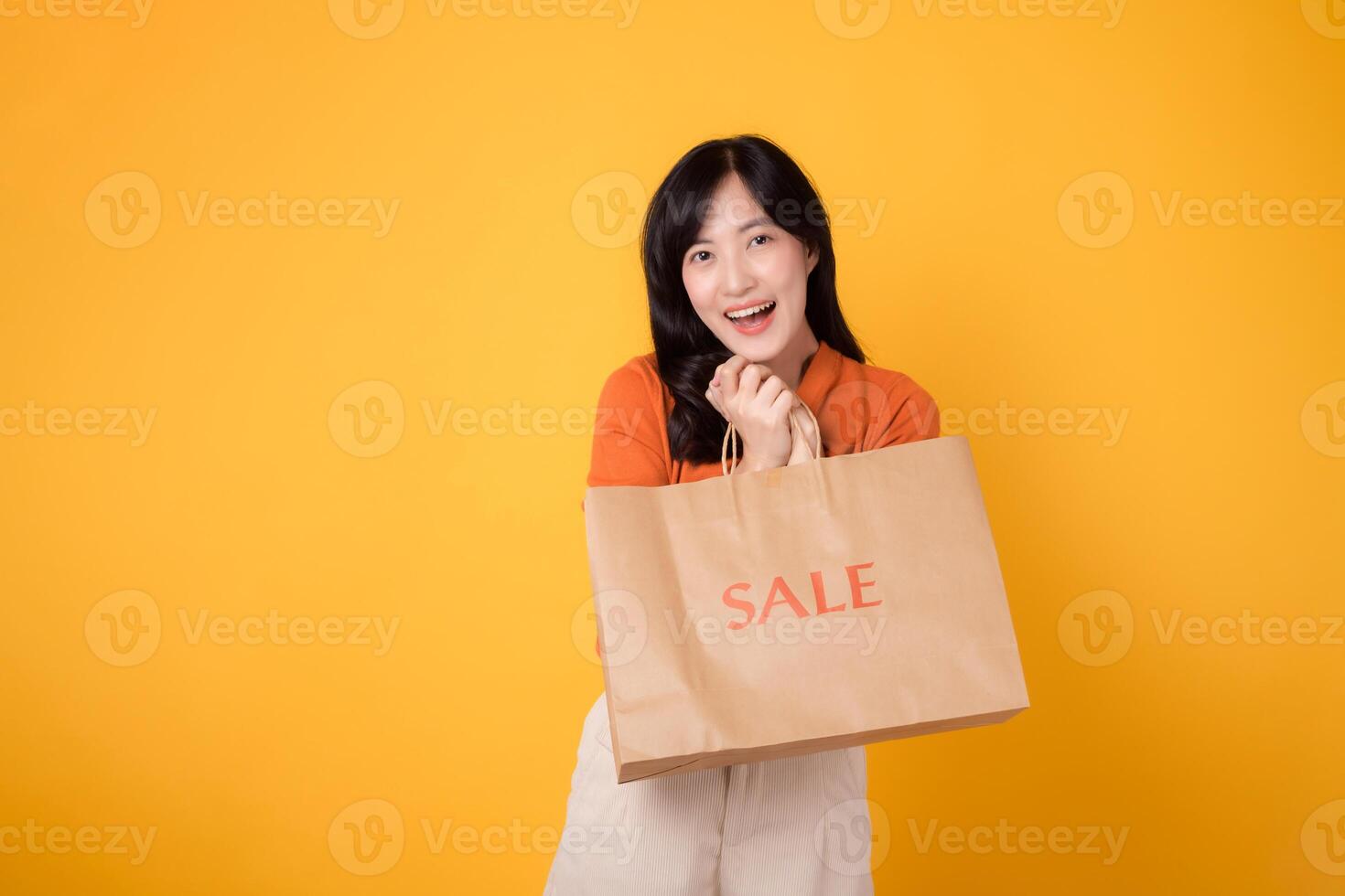 celebrar el alegría de compras con sonrisas y descuentos de moda 30s asiático mujer participación un bolso en un vibrante amarillo antecedentes anuncio concepto. foto