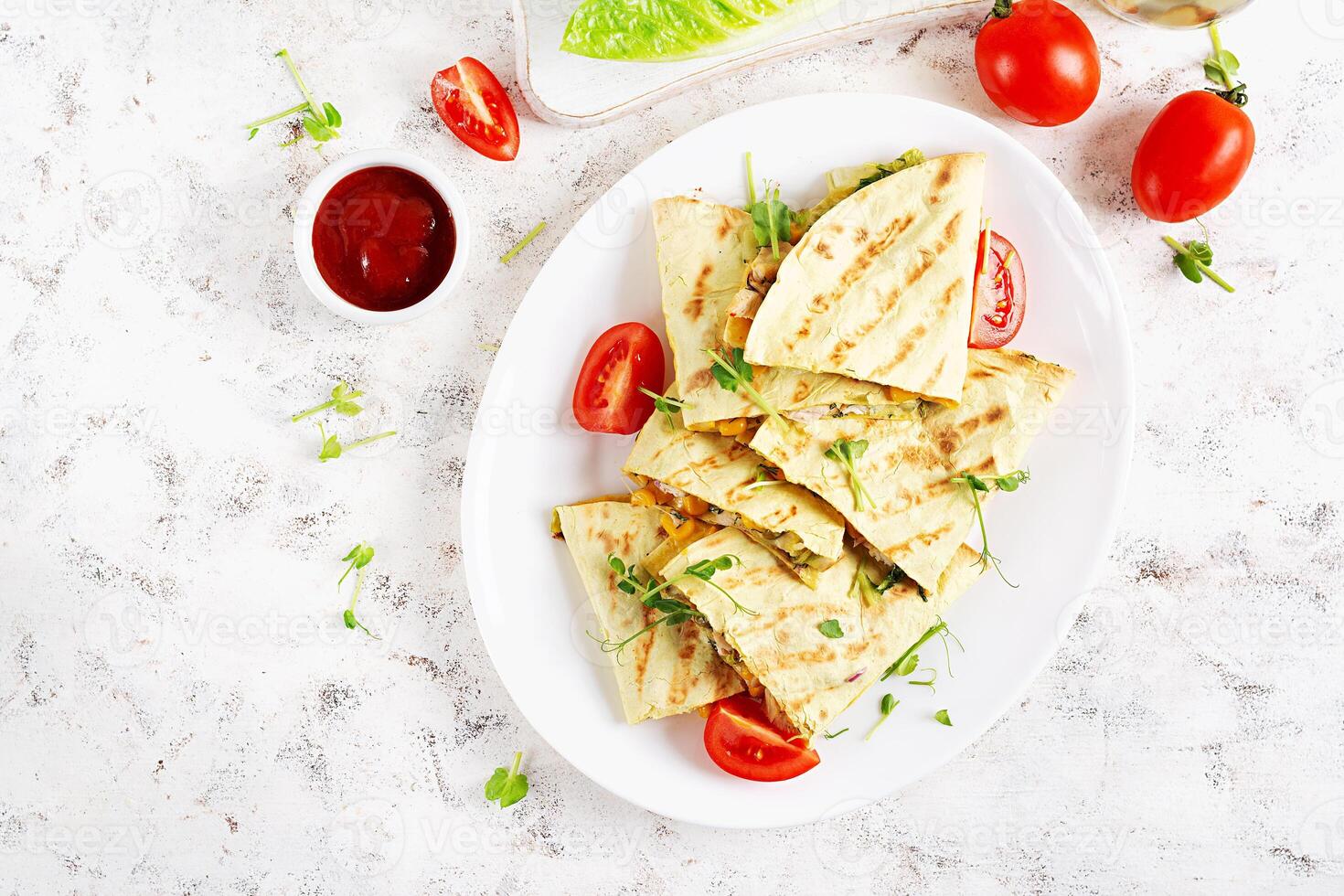 Mexican Quesadilla wrap with chicken, corn and sweet pepper on white plate. Top view photo