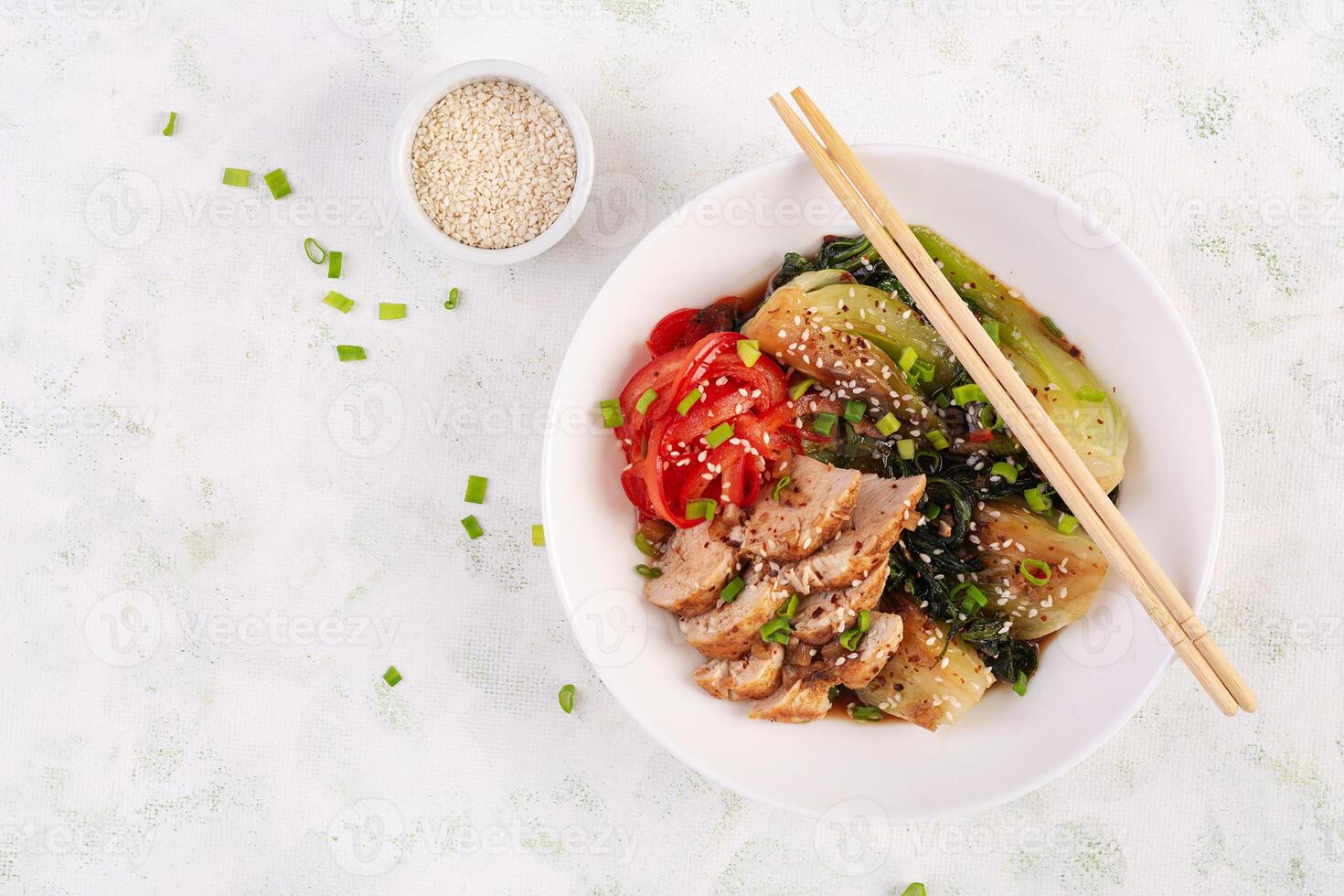 Stir fried of chicken, sweet peppers and bok choy in a bowl on the table. Stir fry pak choi. Asian food. Top view photo