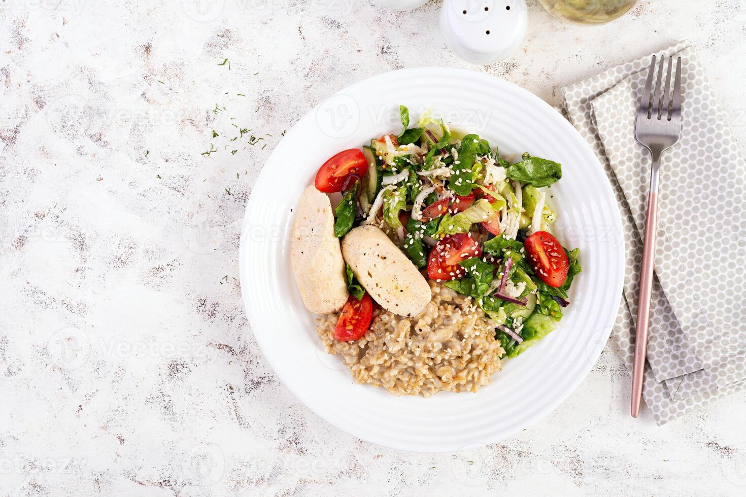 Breakfast oatmeal porridge with boiled homemade chicken sausage and fresh salad. Healthy balanced food. Trendy food. Top view, flat lay photo