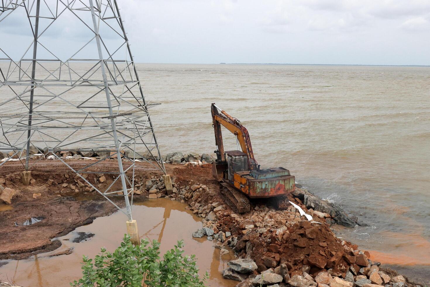 An excavator makes a mound of sand on the seashore.  Protection of the beach area for the winter from flooding. Industrial construction equipment and machinery photo