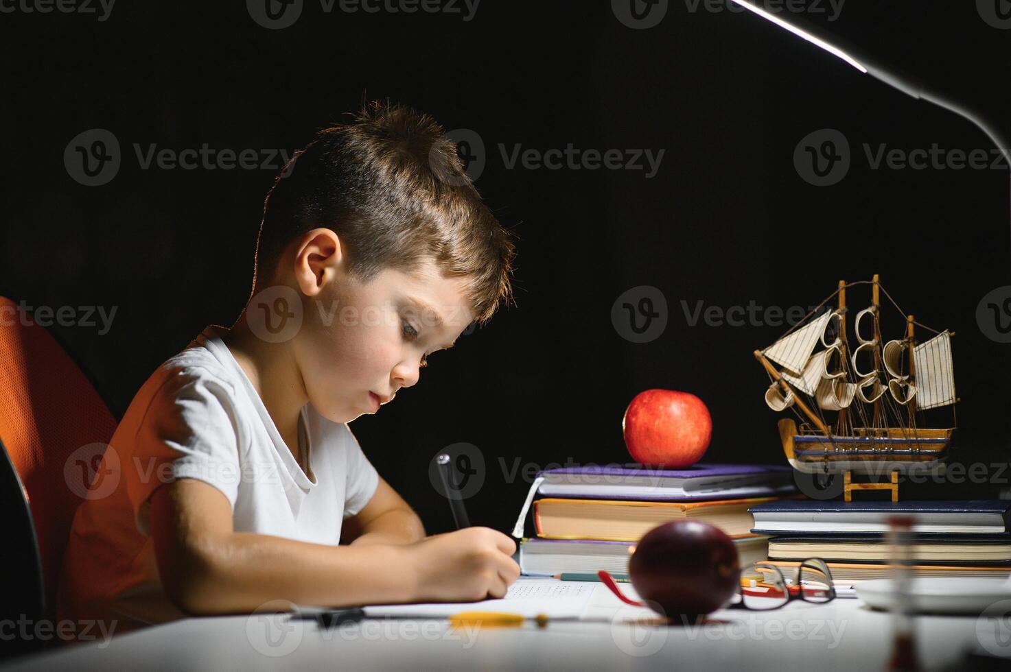 Boy learn lessons in the home setting at the table in the light of a table lamp. photo