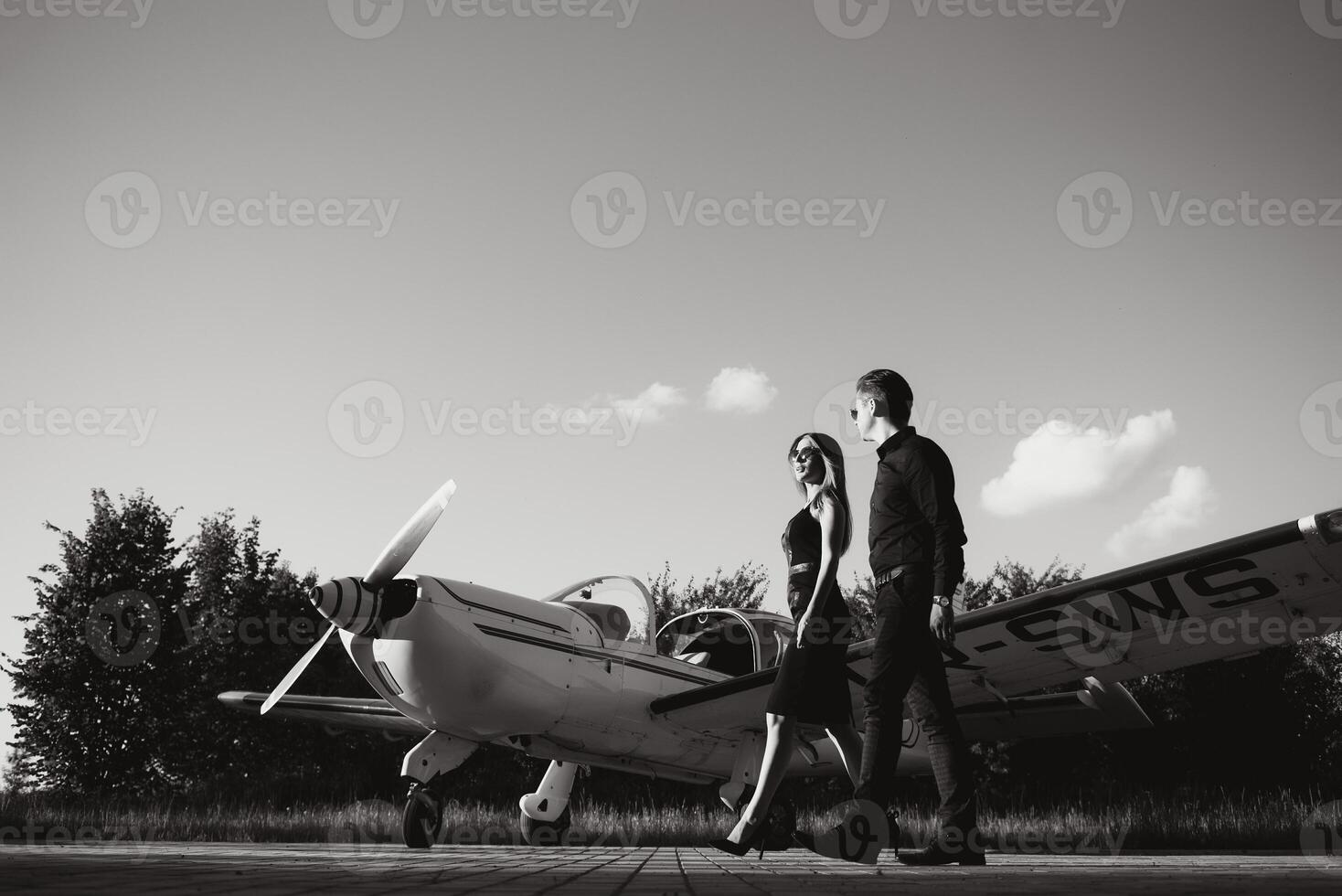 Portrait of two smiling business people, man and woman, walking by plane hangar in airport field photo