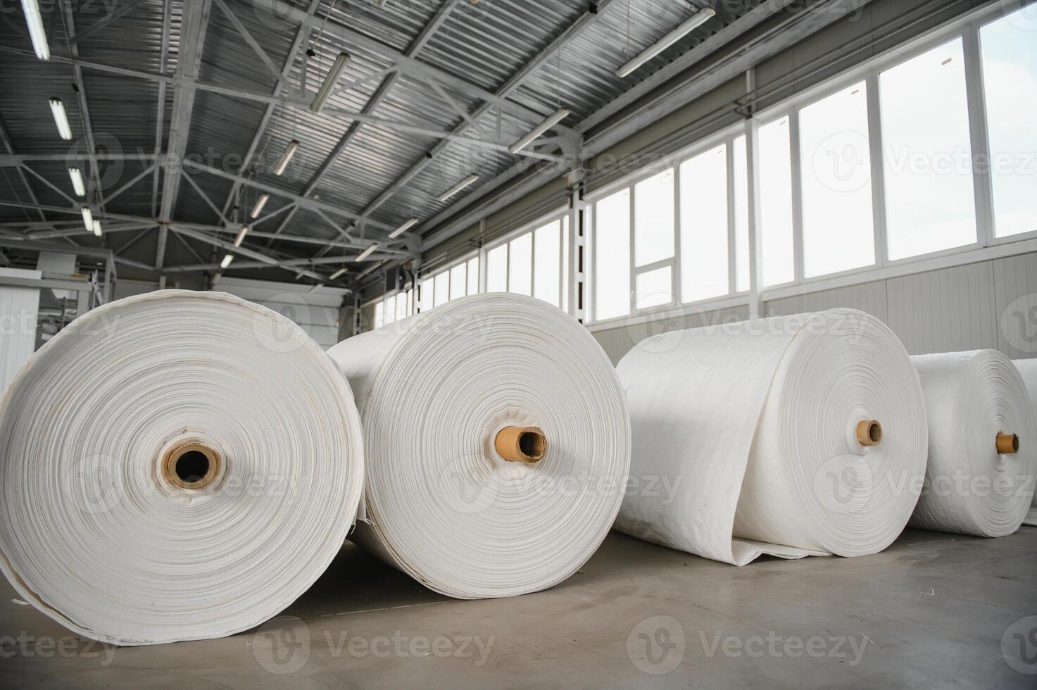 Raw materials warehouse. Many large coils of finished propylene hose made of woven thread for making industrial bags. Polypropylene rolls for packaging. photo
