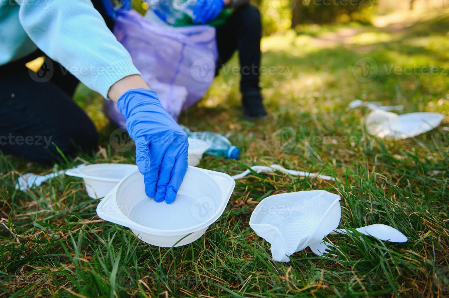 hand puts plastic debris in the garbage bag in the park photo