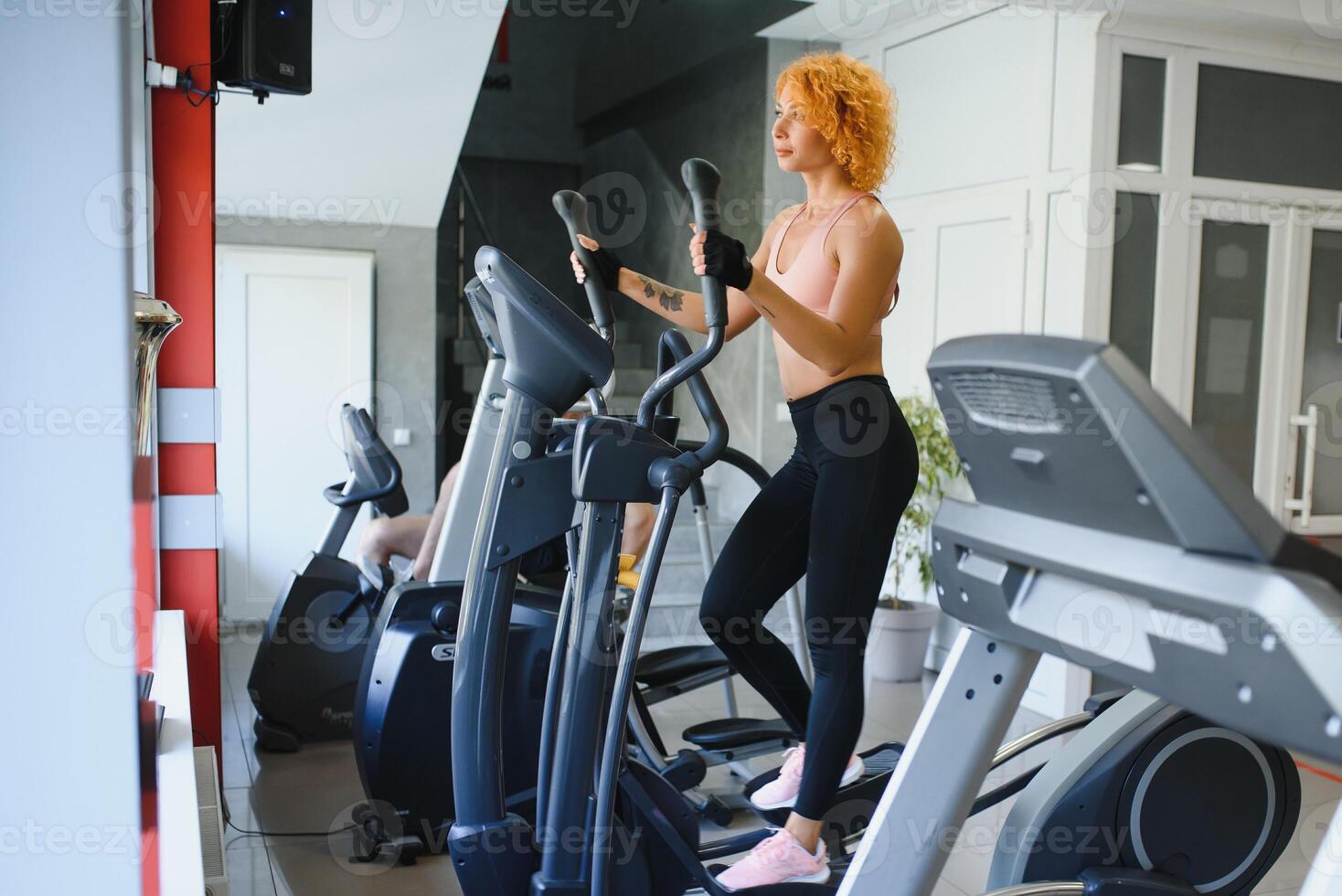 Attractive young sports woman is working out in gym. Doing cardio training on treadmill. Running on treadmill. photo